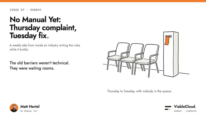 Three empty waiting-room chairs beside a take-a-number dispenser holding one orange ticket.